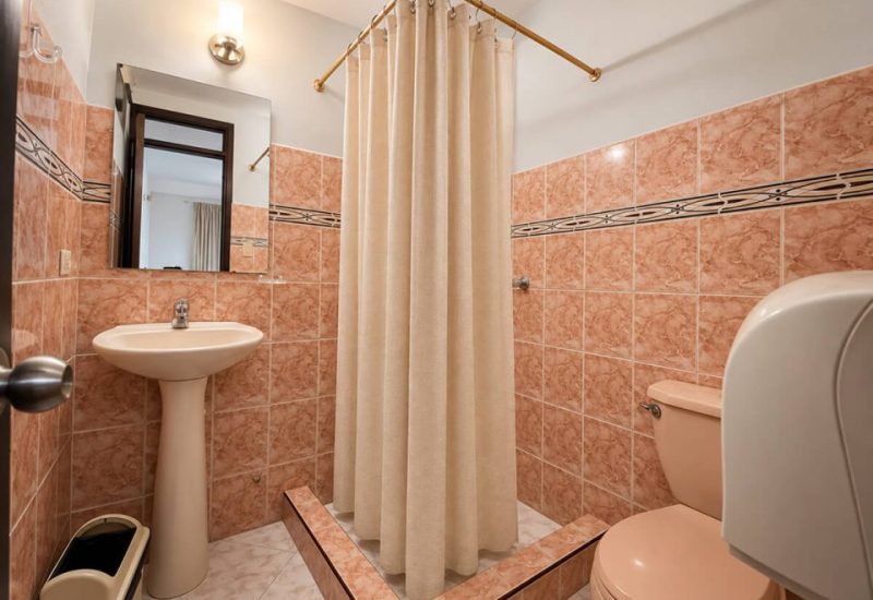Baño con ducha de cortina, lavamanos y enchape de cerámica