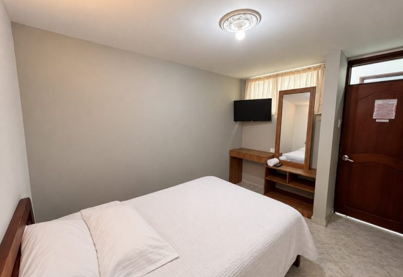 Habitación con cama doble, tocador y televisor