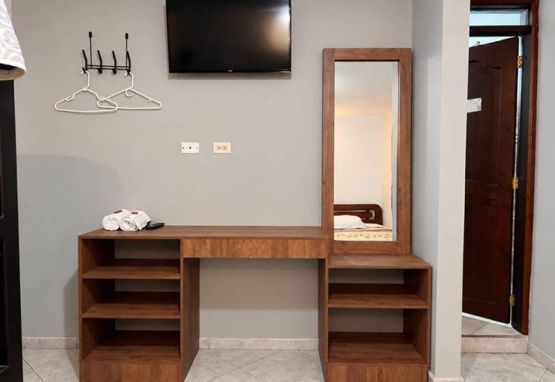 Tocador con espejo, perchero y televisor en una habitación