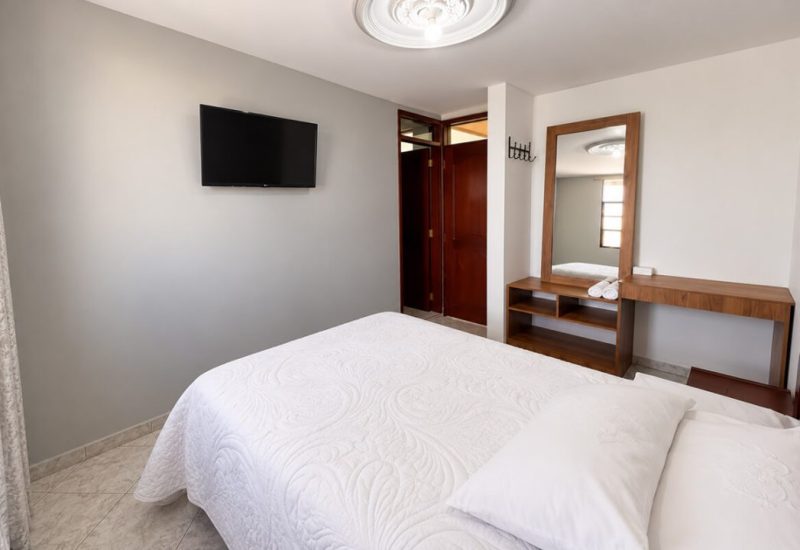 Habitación con cama doble, televisor y tocador