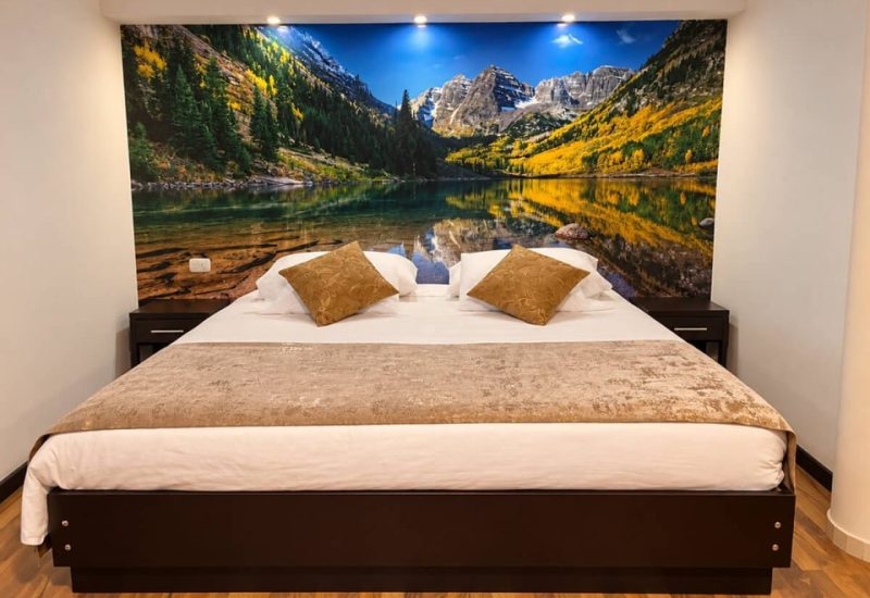 Cama doble con un mural de montañas y lago en la pared
