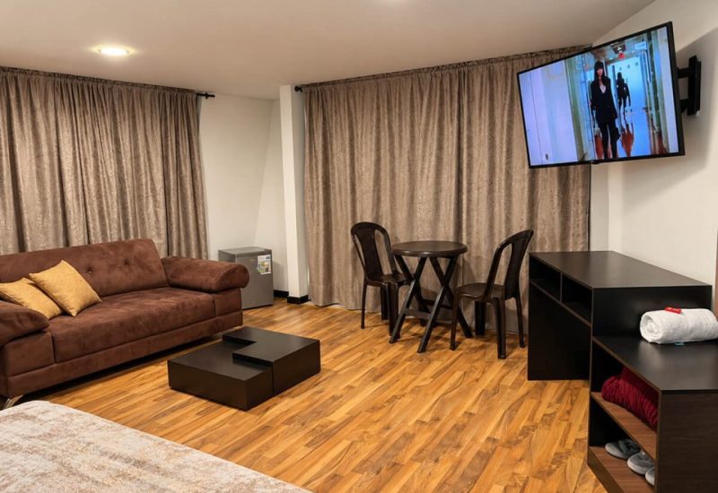 Sala de una suite con sofá, comedor y televisor
