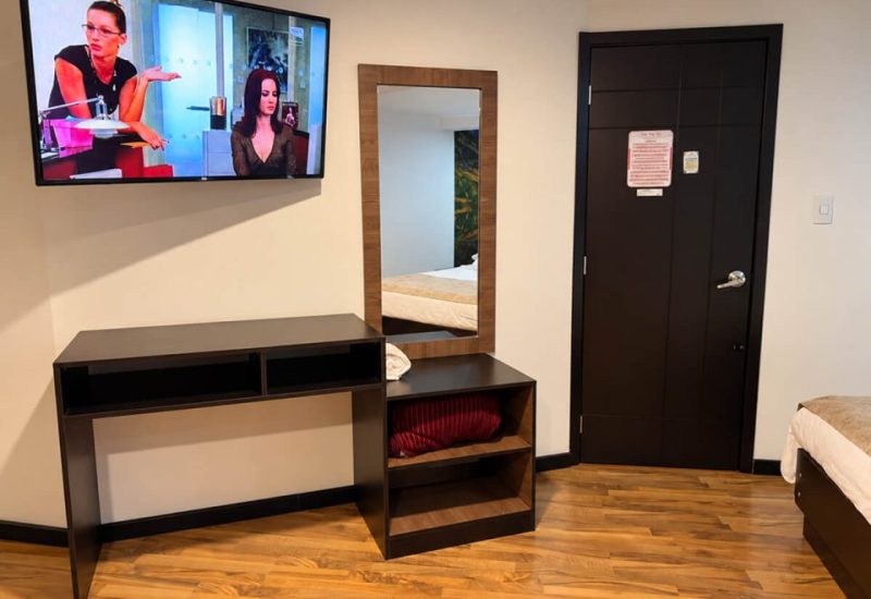 Mueble de televisor, espejo y puerta de una suite