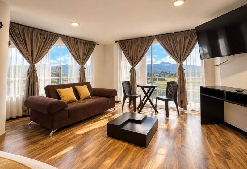 Sala de una suite con sofá, comedor y ventanales con vista a las montañas