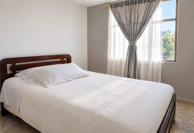 Habitación con cama doble y ventana con cortinas