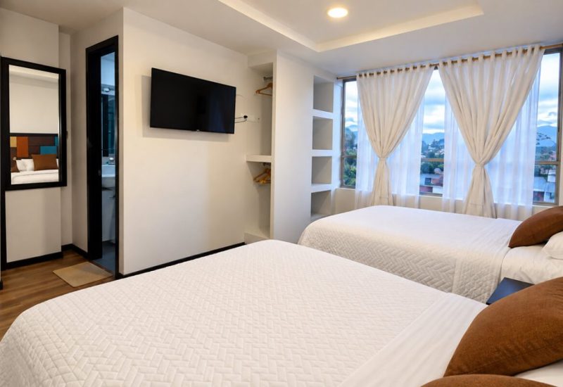 Habitación con camas, televisor y ventanas con cortinas