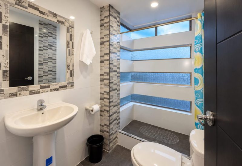 Baño con ducha, lavamanos y espejo con marco de mosaico