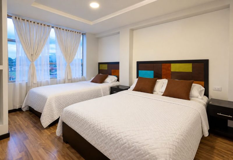 Habitación con cama doble y cama individual junto a dos ventanas