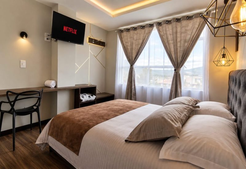 Habitación con cama doble, escritorio y ventana con cortinas