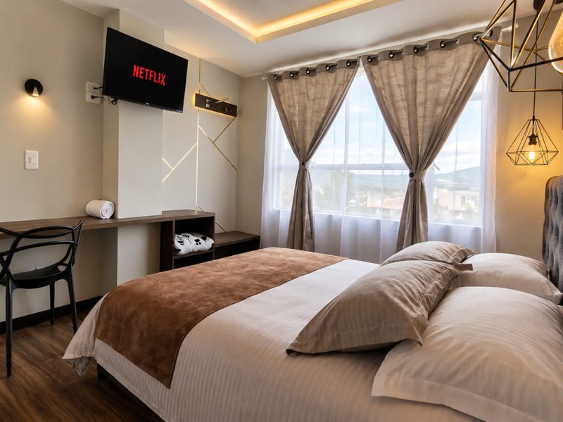 Habitación con cama doble, escritorio y ventana con cortinas