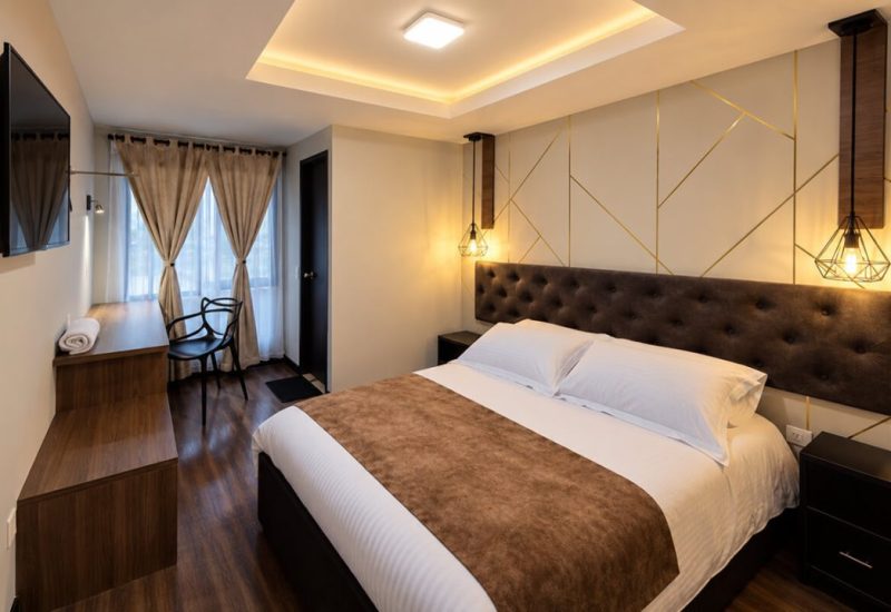 Habitación con cama doble, cabecero acolchado y escritorio junto a la ventana