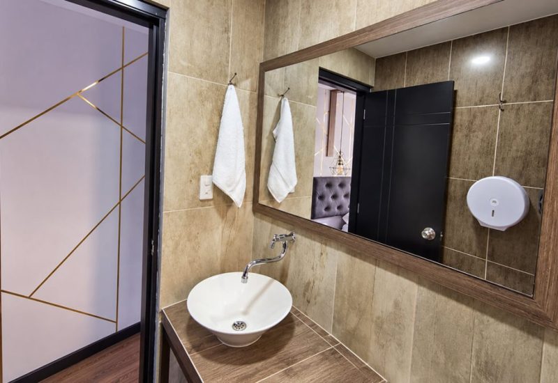 Baño con lavamanos de sobreponer y espejo con marco de madera