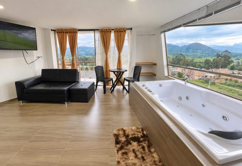 Suite con jacuzzi junto al ventanal y sala con sofá negro