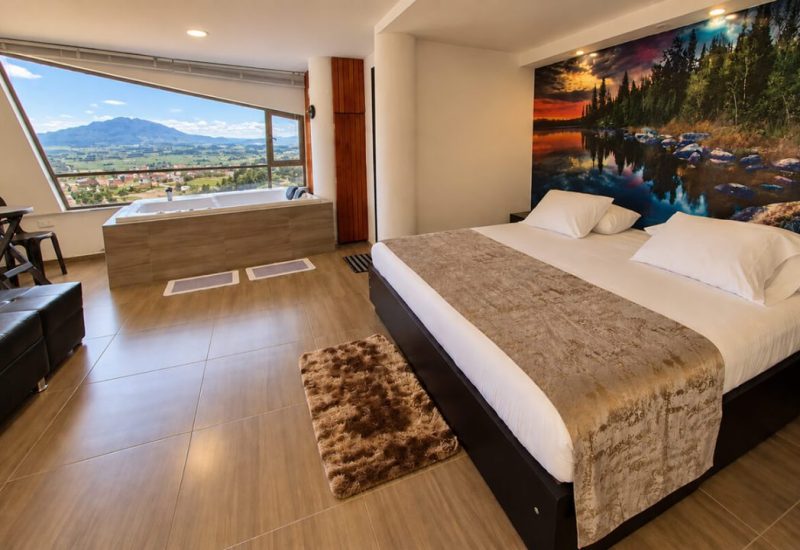 Suite con cama king, jacuzzi junto al ventanal y mural de bosque