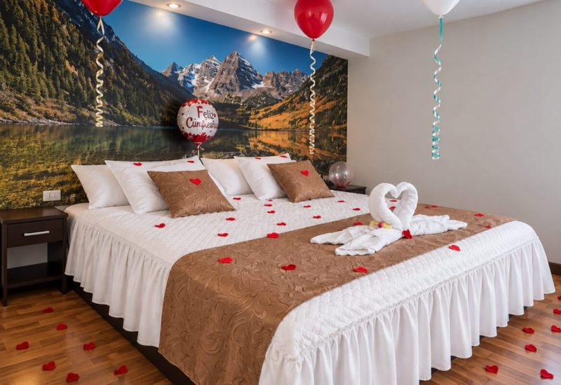 Cama decorada con pétalos, toallas en forma de cisne y globos