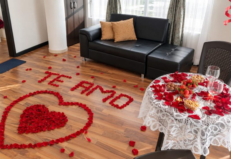 Decoración romántica con pétalos de rosa y la frase «Te amo» en una suite