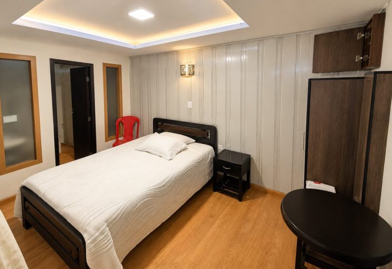 Habitación con cama doble, techo iluminado y piso de madera