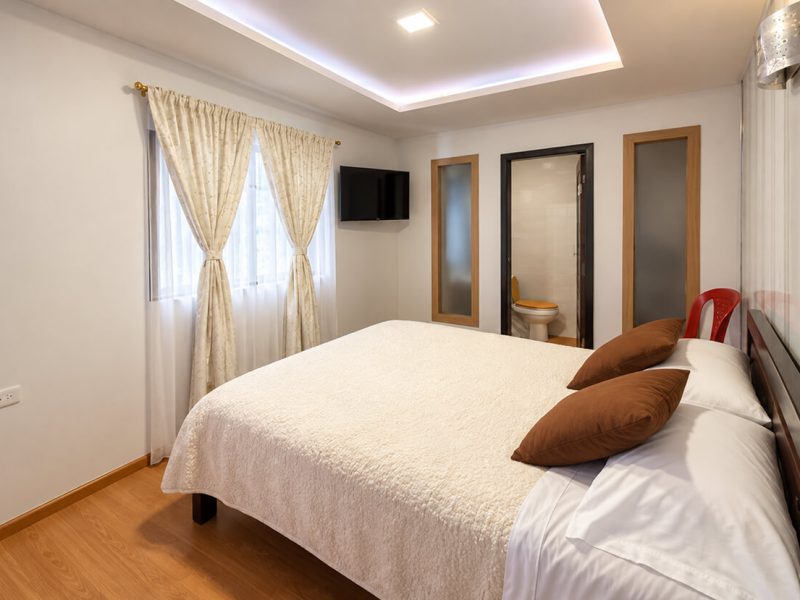 Cama doble con cojines marrones junto a la ventana