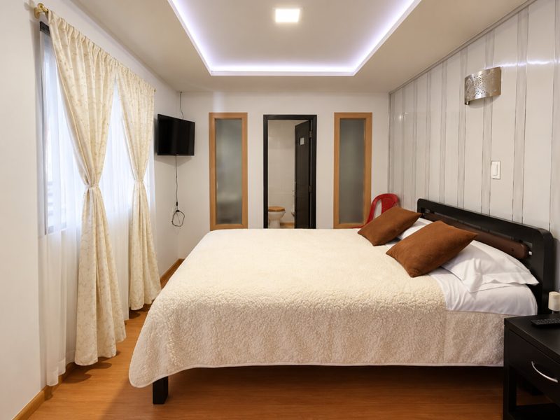 Habitación con cama doble, cojines marrones y cortinas