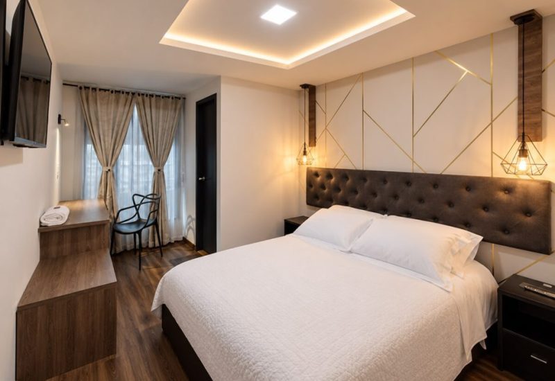 Habitación con cabecero acolchado, escritorio y lámparas colgantes